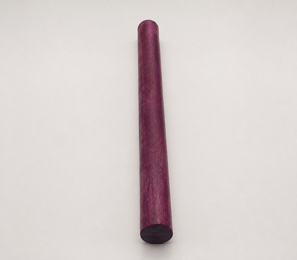 Round Purpleheart wood dowel blank standing upright, showing deep purple heartwood grain for cue building